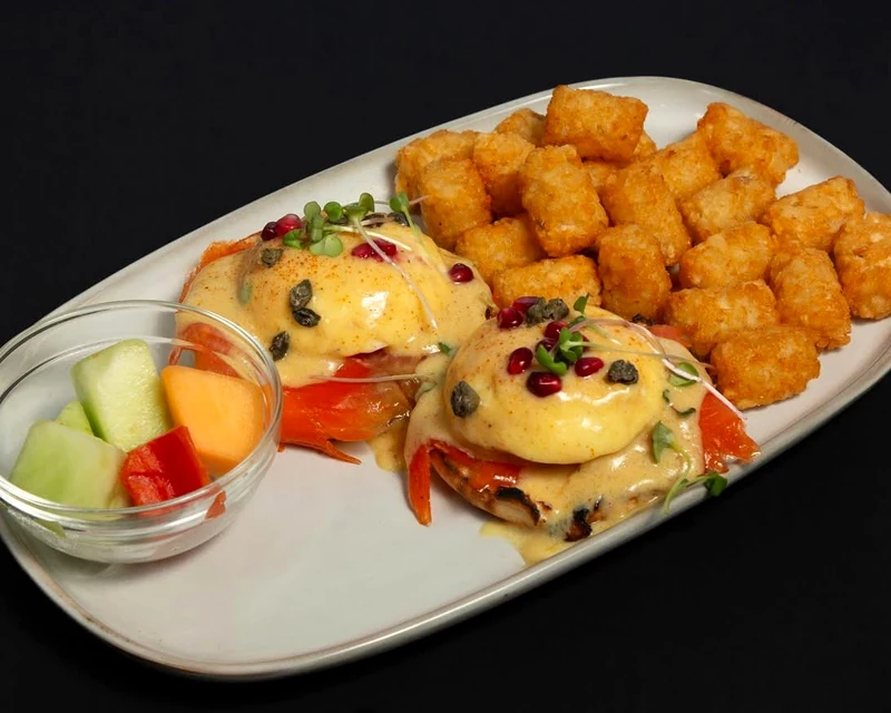 Smoked salmon eggs Benedict with hollandaise, tater tots and fresh fruit at Rise & Dine Restaurant